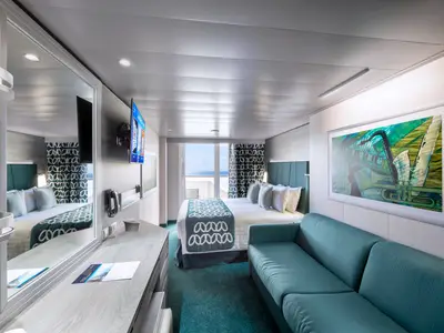 Helle und moderne Balkonkabine an Bord der MSC Virtuosa. Mit Doppelbett, Sofa, Schreibtisch und Balkon mit Meerblick. Einrichtung in Türkis- und Grautönen, mit großem Kunstwerk an der Wand.