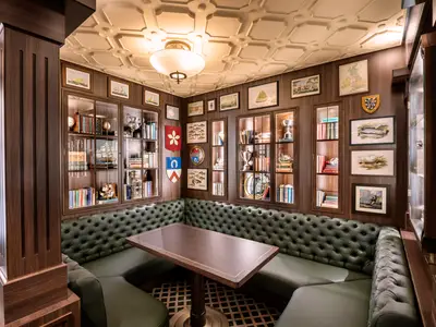 Der Pub 'Masters of the Sea' an Bord der MSC Virtuosa. Dunkle Holzvertäfelung, gruene Chesterfield-Sitzbänke und ein Tisch. Wände mit Buecherregalen und maritimen Bildern.