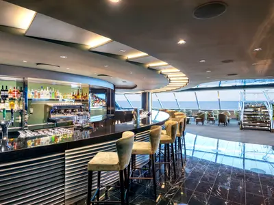 Die stilvolle Top Sail Lounge im MSC Yacht Club der MSC Virtuosa, eine moderne Bar mit grosser Fensterfront und Meerblick.