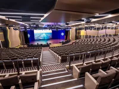 Das Le Grand Théâtre an Bord der MSC Virtuosa. Moderner Theatersaal mit braunen Sitzreihen und beleuchteter Bühne. LED-Wände zeigen Meeresansicht und MSC Logo.