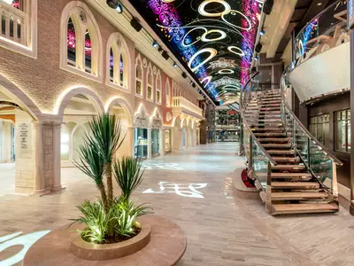 Blick in die luxuriöse Galleria Virtuosa an Bord der MSC Virtuosa. Eine breite Promenade mit Geschäften, einer geschwungenen Treppe und einem beeindruckenden LED-Himmel.