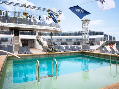 Blick auf den Horizon Pool an Bord der MSC Virtuosa, umgeben von einem Holzdeck mit grauen Sonnenliegen. Eine Elefantenskulptur blickt auf den Pool, im Hintergrund sind weitere Schiffdecks zu sehen.