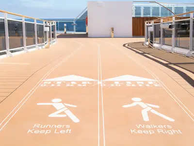 Die Power-Walking-Strecke an Bord der MSC Virtuosa bei Tageslicht. Läufer halten sich links, Spaziergänger rechts. Distanzangaben (0,33 km) und das offene Meer sind sichtbar.