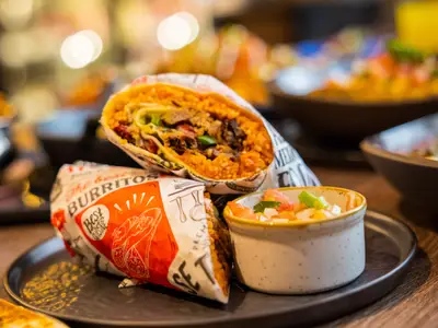 Appetitliche Burritos mit Reis und Fleisch, serviert mit Pico de Gallo an Bord der MSC Virtuosa. Der Hintergrund ist unscharf mit warmen Lichtern.