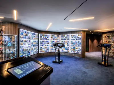 Die moderne Fotogalerie an Bord der MSC Virtuosa. Grosse Bildschirme zeigen Fotos. Interaktive Terminals und Kameravitrinen in einem eleganten Raum.