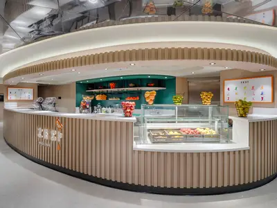 Moderne Zest Juice Bar an Bord der MSC World America. Helle Holztheke mit frischen Äpfeln, Orangen und Limetten in Körben. Bunte Saftkarte an der Wand. Einladende, frische Atmosphäre.