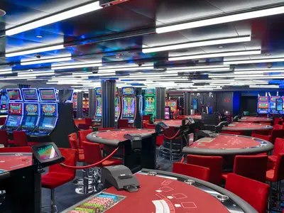 Ein modernes Casino an Bord der MSC World America mit leuchtenden Spielautomaten und roten Spieltischen. Die helle, dynamische Beleuchtung lädt zum Verweilen ein.