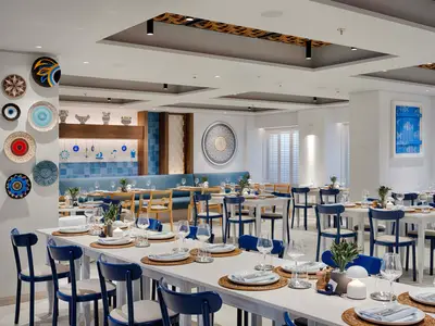 Ein stilvolles, maritim inspiriertes Restaurant an Bord der MSC World America, dekoriert mit blauen Akzenten, Rattanstühlen und liebevoll gedeckten Tischen für die Gäste.
