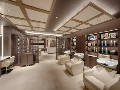 Ein eleganter Friseursalon im MSC Aurea Spa an Bord der MSC World America. Helle Sitze, Waschbecken, Produktregale und Holzelemente prägen den Raum.