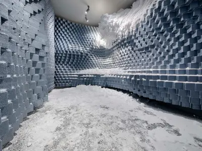 Eine künstliche Eishöhle im Thermalbereich des MSC Aurea Spa an Bord der MSC World America. Die Wände bestehen aus gestuften, grauen Blöcken, bedeckt mit weißem Pulverschnee am Boden und an den Wänden.