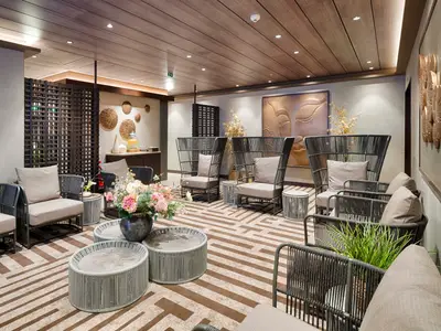 Ein stilvoller Lounge-Bereich des MSC Aurea Spa an Bord der MSC World America. Der Raum bietet bequeme Sessel, runde Tische, ein Erfrischungsbuffet und Wandkunst.