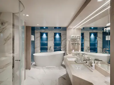 Luxuriöses Badezimmer der Owner's Suite an Bord der MSC World America mit freistehender Badewanne, Doppelwaschbecken und verglaster Dusche. Modernes Design mit Marmor und blauen Akzenten.