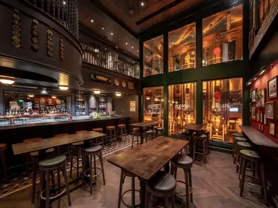 Blick in die rustikale Bar 'Masters of the Sea' an Bord der MSC World Asia mit langem Bartresen, Tischen und einer integrierten Mikrobrauerei hinter Glas.