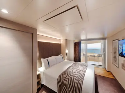Geräumige, barrierefreie Balkonkabine an Bord der MSC World Asia. Zu sehen sind ein Doppelbett, ein moderner TV und ein Balkon mit Meerblick.
