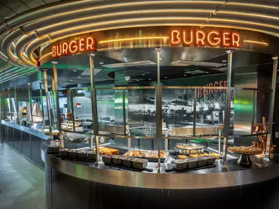 Modernes Burger-Restaurant an Bord der MSC World Asia. Helle Neon-Schilder, Theken mit Burgern und Beilagen. Sauber und hell.