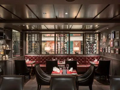 Blick in das dunkle, elegante Steakhouse Butcher's Cut an Bord der MSC World Asia. Rote Lederbänke, dunkle Tische, viele Weinflaschen und Ochsen-Dekorationen prägen den Raum.