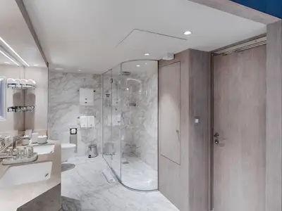 Ein luxuriöses Badezimmer an Bord der MSC World Asia Owner's Suite, ausgestattet mit zwei Waschbecken, einer begehbaren Glasdusche und eleganten Marmorfliesen an Wänden und Boden.