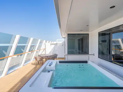Balkon einer MSC Yacht Club Owner's Suite an Bord der MSC World Asia mit privatem Whirlpool, Sitzmöbeln und Meerblick unter blauem Himmel.
