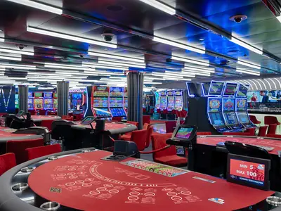 Modernes MSC Signature Casino an Bord der MSC World Atlantic. Der große Raum zeigt rote Spieltische, leuchtende Slotmaschinen und eine Bar. LED-Lichtstreifen zieren die Decke.