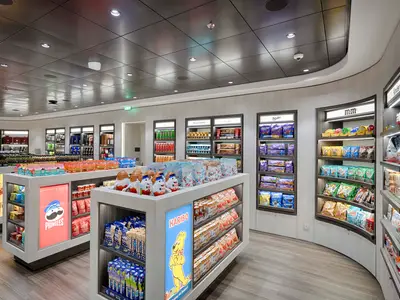 Blick in einen hell beleuchteten, modernen Shop an Bord der MSC World Atlantic mit Regalen voller Süßigkeiten, Chips und Alkoholika. Die Einrichtung ist hell und geräumig.
