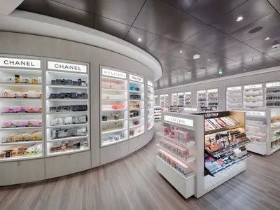 Ein heller, moderner Shop an Bord der MSC World Atlantic mit beleuchteten Regalen voller Parfuems und Kosmetik von Marken wie Chanel, Bvlgari und Dior.