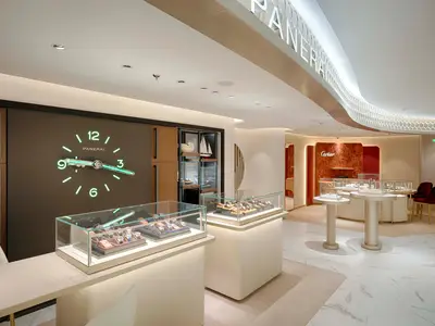 Luxuriöser Uhrenshop Time Vallée an Bord der MSC World Atlantic. Panerai und Cartier Uhren in Vitrinen. Große leuchtende Panerai-Wanduhr und roter Cartier-Bereich sind sichtbar.