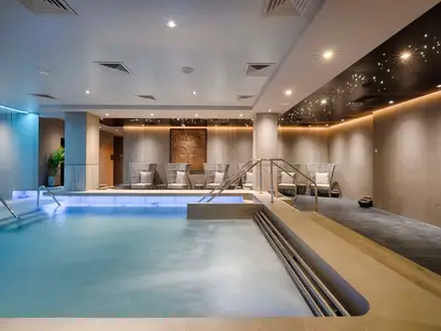 Modernes MSC Aurea Spa an Bord der MSC World Atlantic mit Pool, Thermalbereich, Lounge-Sesseln und Buddha-Skulptur. Entspannte Atmosphäre.