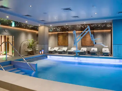 Spa-Poolbereich an Bord der MSC World Atlantic. Blauer Pool mit Dampf und Lifter. Liegen, Hängesessel, Buddha-Kunst und funkelnde Lichter.