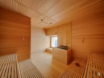 Eine helle, moderne Holzsauna an Bord der MSC World Atlantic. Helles Holz kleidet den Raum aus. Sicht auf das Meer durch ein Fenster. Ein Saunaofen ist in der Mitte zu sehen. Ohne Personen.