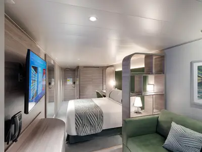 Eine moderne Aussenkabine an Bord der MSC World Europa. Sie zeigt ein Doppelbett mit gemusterter Decke, ein grünes Sofa, einen Flachbildfernseher und einen Schreibtisch. Die Einrichtung ist hell und stilvoll.