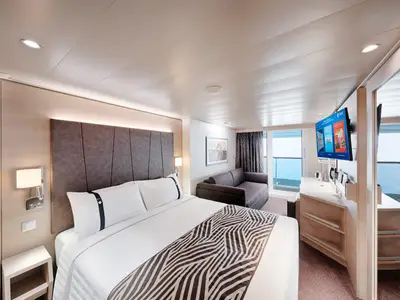 Helle Balkonkabine an Bord der MSC World Europa. Grosses Doppelbett, Sofa und Flachbild-TV. Privater Balkon mit Meerblick. Modern und elegant eingerichtet.
