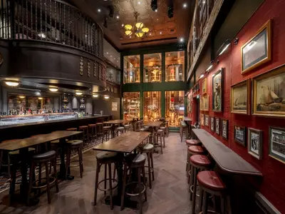 Ein gemütliches Pub mit langer Bar und eigener Brauerei an Bord der MSC World Europa. Dunkle Holztische, Barhocker und eine rote Ziegelwand mit gerahmten Bildern schaffen eine klassische Atmosphäre.