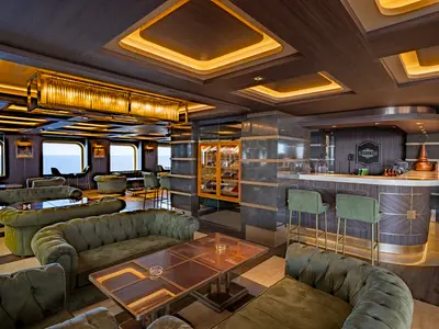 Die stilvolle Lanai Bar an Bord der MSC World Europa. Grüne Samtsofas, dunkles Holz, Marmor, goldene Akzente und große Fenster mit Meerblick kennzeichnen die luxuriöse Lounge.