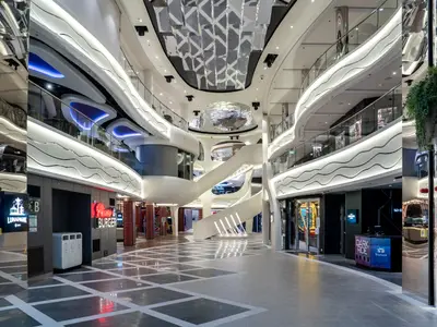 An Bord der MSC World Europa: die moderne World Galleria. Shops, Restaurants und Unterhaltung wie Luna Park. Helle Architektur, Glasgeländer, Wendeltreppe.