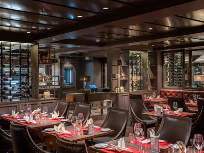 Innenansicht des stilvollen Spezialitätenrestaurants Butcher's Cut an Bord der MSC World Europa mit gedeckten Tischen und Weinregalen.