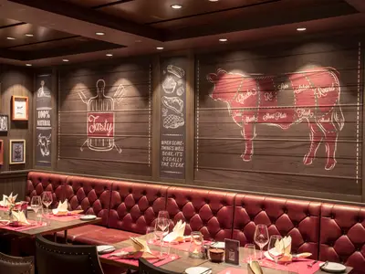 Das Steakhouse Butcher's Cut an Bord der MSC World Europa zeigt rote Lederbänke, Holzwände mit Metzger-Motiven und gedeckte Tische. Ein gemütliches Ambiente.