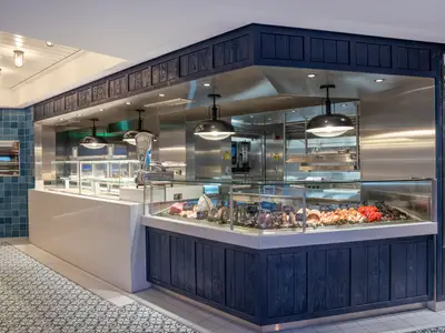 Spezialitaetenrestaurant La Pescaderia an Bord der MSC World Europa. Frische Meeresfruechte und Fisch auf Eis in der Theke, umgeben von modernen Kuechenelementen.