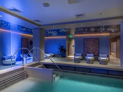 Der Thermalbereich der MSC World Europa mit hellblau beleuchtetem Innenpool, Loungesesseln und sternförmigen Lichtern an der Decke.