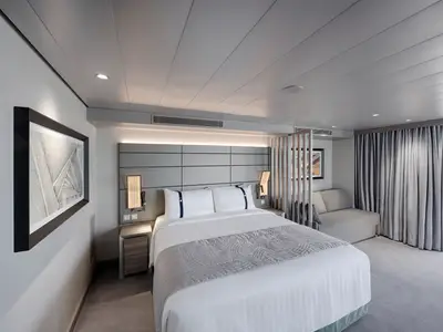 Helle Grand Suite Aurea an Bord der MSC World Europa mit einem gemütlichen Doppelbett, Nachttischen, einem bequemen Sofa und einem Balkon mit Meerblick. Moderne Einrichtung mit Holz- und Grautönen.