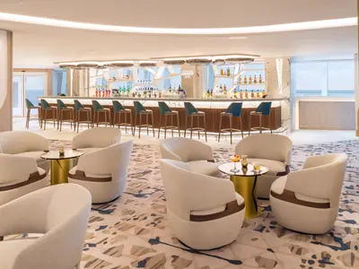 Die Belvedere Bar an Bord der Norwegian Aqua. Moderne Bar mit Barhockern und Lounge-Sesseln. Getraenke auf Tischen. Fenster mit Meerblick.
