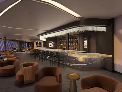 Elegante Bar-Lounge an Bord der Norwegian Aqua mit langer Theke, Barhockern, diversen Sesseln und Tischen. Die Decke ist geschwungen mit indirekter Beleuchtung und einem kristallähnlichen Leuchter über der Bar. Grosse Fenster bieten Ausblick nach draussen.