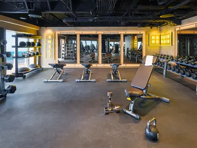 Das moderne Fitnesscenter an Bord der Norwegian Aqua mit Meerblick. Zahlreiche Hanteln, Kettlebells und Trainingsbänke stehen bereit. Motivierende Neonleuchtschriften zieren die Wände.