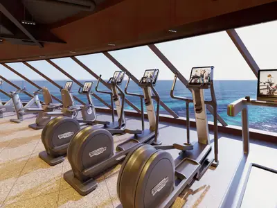 Das moderne Fitnesscenter der Norwegian Aqua zeigt Cardiogeräte wie Ellipsentrainer und Fahrräder. Große Fenster bieten einen Panoramablick auf das Meer.