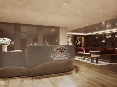 Blick auf den eleganten Empfangsbereich des Mandara Spa an Bord der Norwegian Aqua. Eine geschwungene Rezeption mit leuchtendem Logo und ein gediegener Loungebereich sind zu sehen.