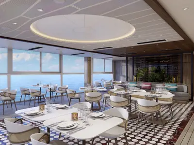 Das Spezialitätenrestaurant Palomar an Bord der Norwegian Aqua. Weisse Tische, helle Korbstühle und grosse Fenster bieten einen weiten Blick auf das offene Meer.