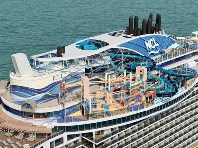 Luftaufnahme eines Renderings der Norwegian Aura, die den Aqua Park und den Abenteuerbereich mit Wasserrutschen und einem Hochseilgarten auf dem Oberdeck in einem Teilschnitt zeigt. Im Hintergrund das Meer.