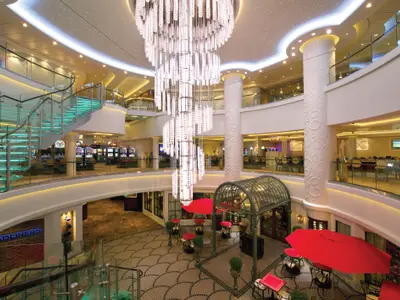 Das Atrium der Norwegian Breakaway. Zu sehen sind ein großer Kronleuchter, eine beleuchtete Glaswendeltreppe, Restaurants und ein Casino.