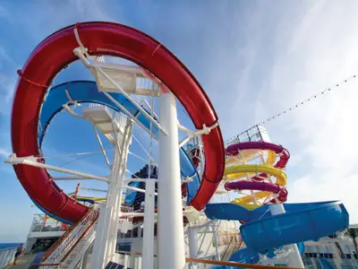 Die farbenfrohe Wasserrutschenanlage an Deck der Norwegian Breakaway unter blauem Himmel. Rote, blaue, gelbe und violette Rutschen schlängeln sich. Keine Personen sichtbar.