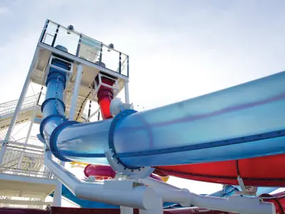 Detailaufnahme der farbenfrohen Wasserrutschen an Deck der Norwegian Breakaway, die sich unter hellem Himmel in die Länge schlängeln.