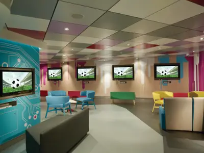 Eine lebhafte Gaming-Lounge an Bord der Norwegian Breakaway. Mehrere Bildschirme zeigen Fussball, umgeben von bunten Sitzgelegenheiten und modernen Wanddekorationen. Ein kinderfreundlicher Bereich.